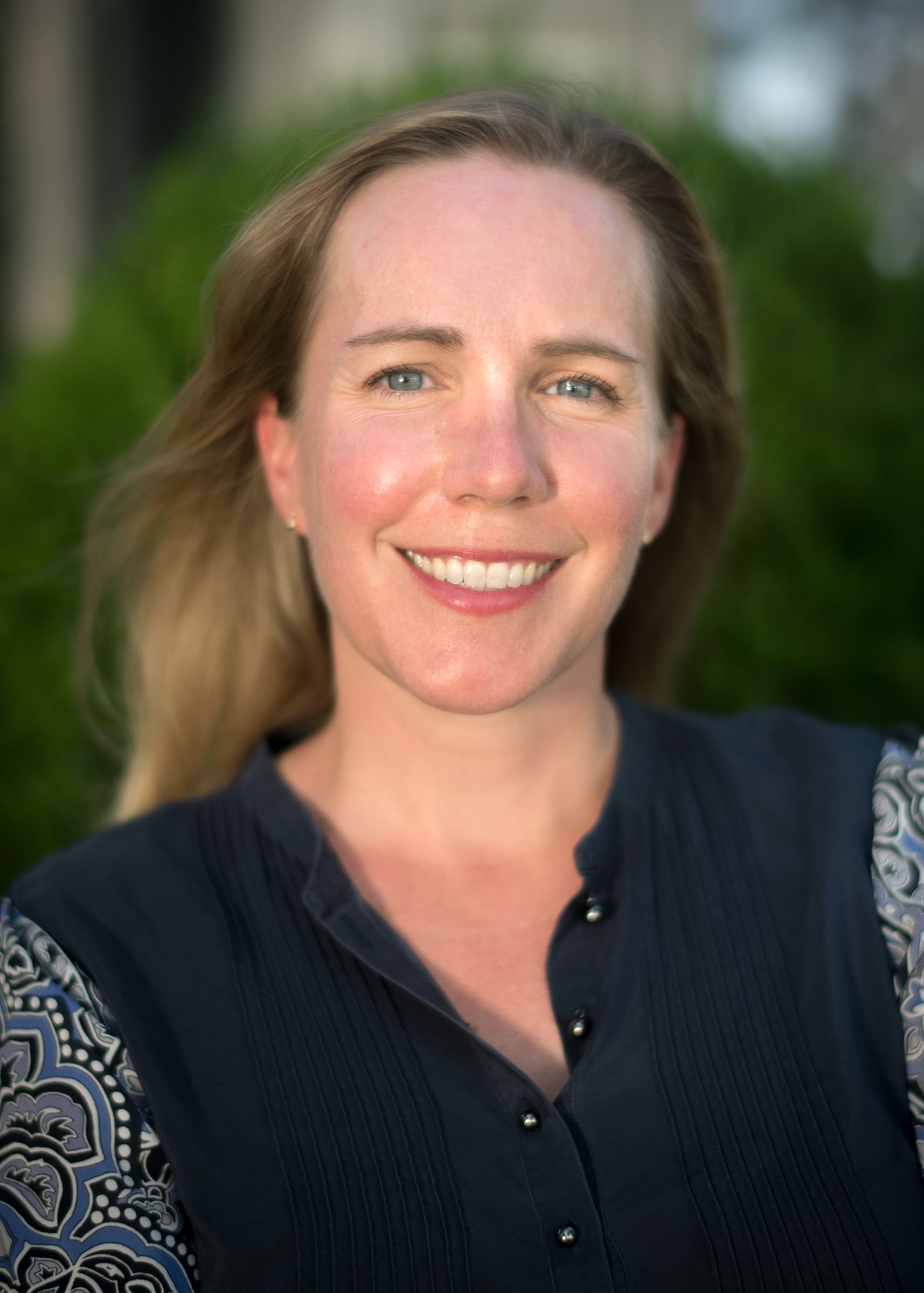 A photo of Laura Helmke Long in a black shirt with blue paisley sleeves. 